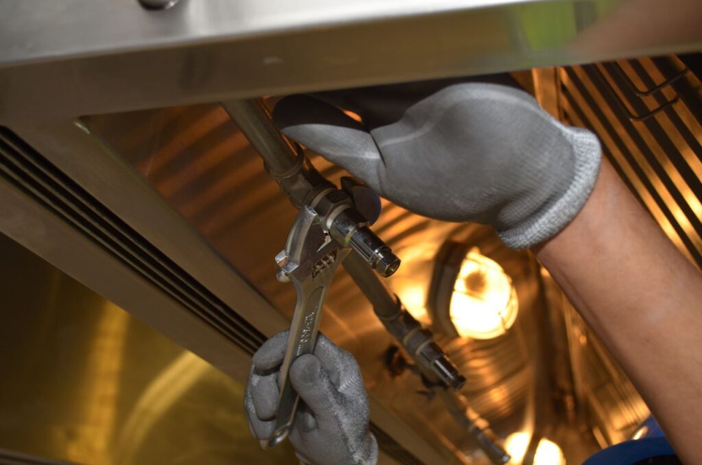 A worker fixing pipes with tools in an industrial indoor environment.